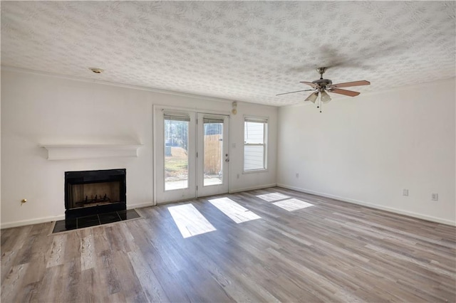 unfurnished living room with light wood-type flooring, a fireplace with flush hearth, baseboards, and a textured ceiling