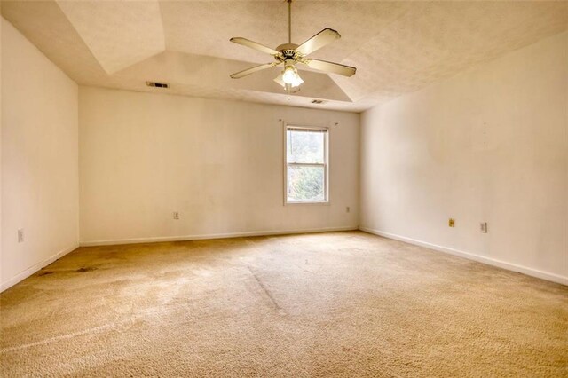 spare room featuring carpet floors, visible vents, baseboards, a ceiling fan, and a tray ceiling