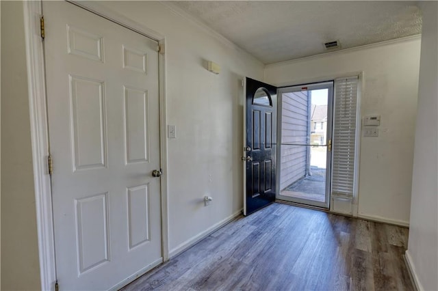entrance foyer with light wood-style floors, visible vents, crown molding, and baseboards