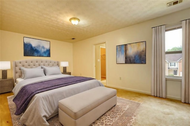 bedroom featuring baseboards, visible vents, a walk in closet, and a textured ceiling
