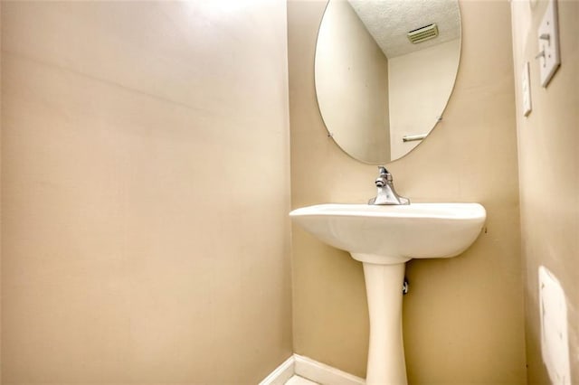 bathroom featuring baseboards, visible vents, and a textured ceiling