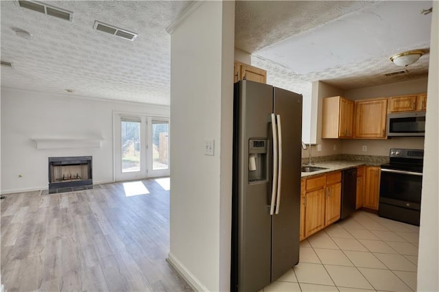 kitchen with a textured ceiling, a sink, open floor plan, light countertops, and black appliances