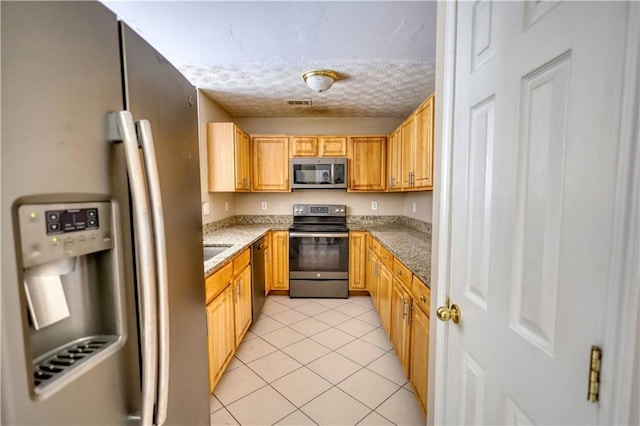 kitchen with light tile patterned floors, visible vents, appliances with stainless steel finishes, a textured ceiling, and stone counters