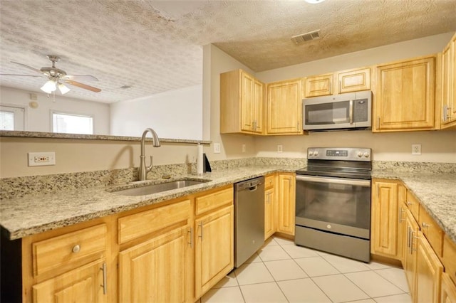 kitchen with stainless steel appliances, a sink, visible vents, and light stone countertops