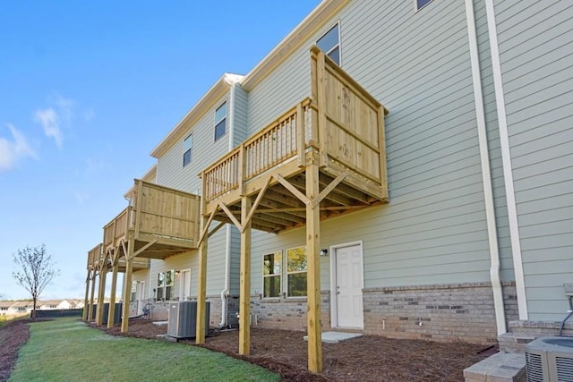 rear view of house with a wooden deck, cooling unit, and a yard