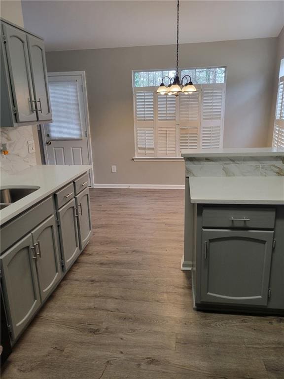 kitchen with gray cabinetry, dark wood-type flooring, baseboards, light countertops, and decorative backsplash