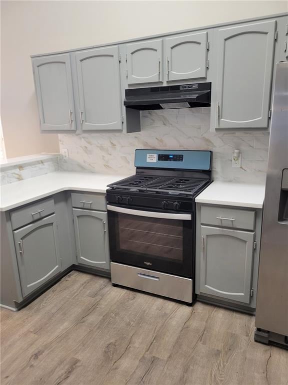 kitchen featuring light countertops, appliances with stainless steel finishes, gray cabinets, and under cabinet range hood