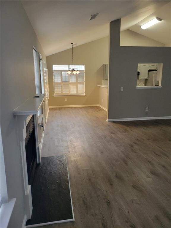 unfurnished living room with lofted ceiling, visible vents, baseboards, dark wood finished floors, and an inviting chandelier