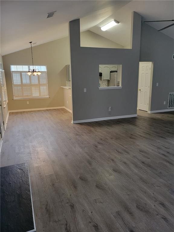 unfurnished living room with visible vents, dark wood finished floors, baseboards, and an inviting chandelier