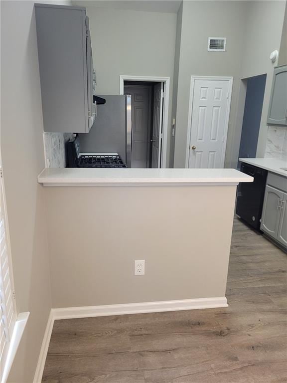 kitchen with light wood finished floors, gray cabinets, visible vents, dishwasher, and a peninsula