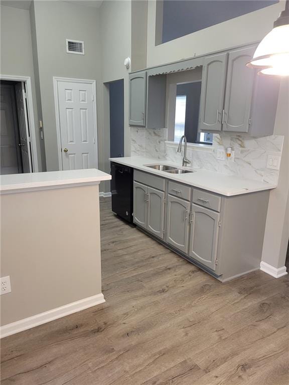 kitchen featuring black dishwasher, a sink, visible vents, and gray cabinetry