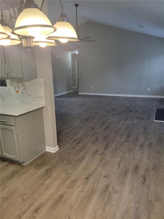 kitchen with lofted ceiling, light countertops, baseboards, and wood finished floors