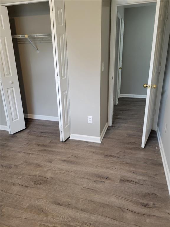 unfurnished bedroom featuring a closet, wood finished floors, and baseboards