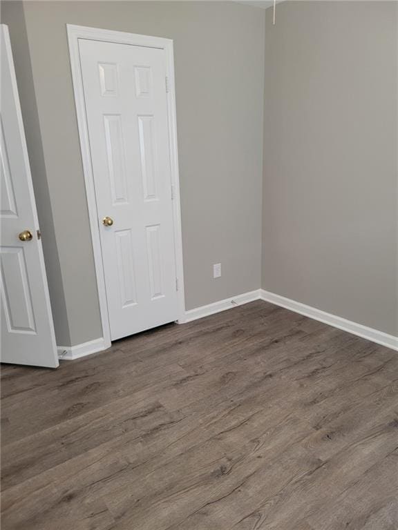 spare room featuring dark wood-style floors and baseboards