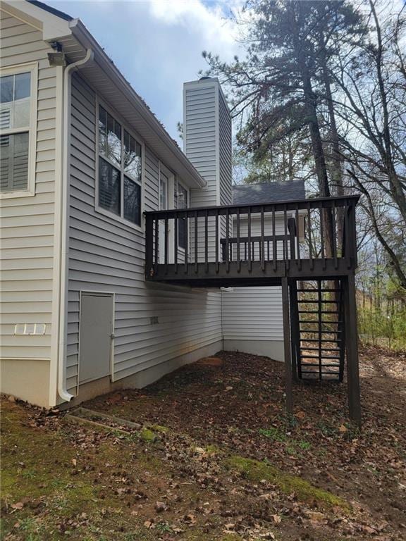 rear view of house with a deck, a chimney, and stairs