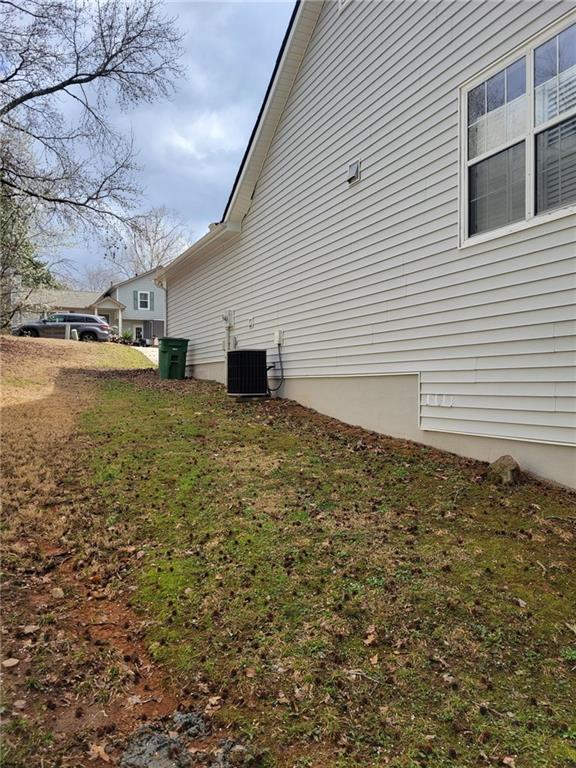 view of side of property with cooling unit and a lawn