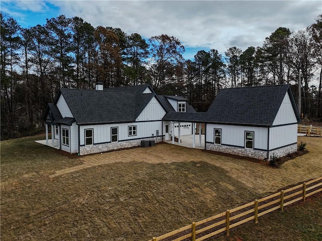 modern farmhouse with a front yard, central air condition unit, and a patio