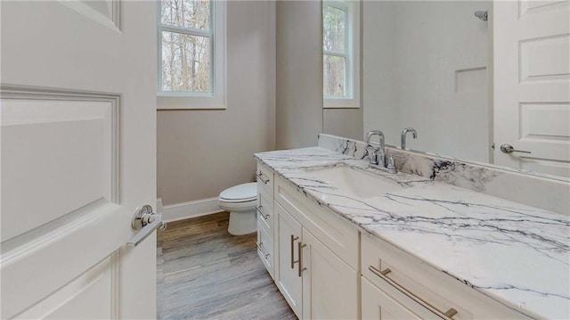 bathroom featuring toilet, plenty of natural light, wood-type flooring, and vanity