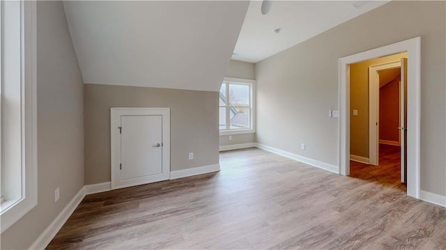 additional living space with light hardwood / wood-style flooring and lofted ceiling