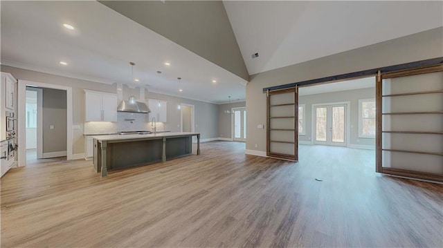 kitchen featuring white cabinetry, an island with sink, a kitchen breakfast bar, hanging light fixtures, and a barn door