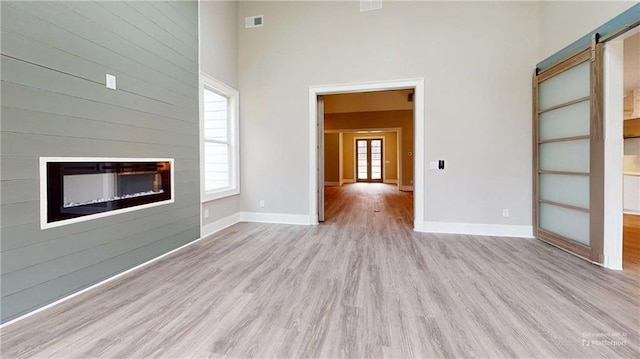 unfurnished living room with a wealth of natural light, light hardwood / wood-style flooring, and a barn door