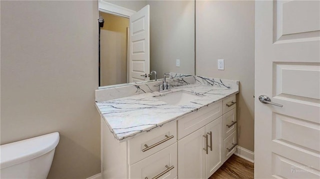 bathroom with hardwood / wood-style floors, toilet, and vanity