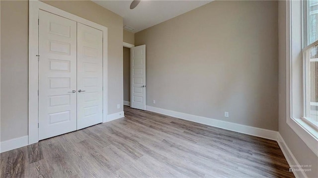 unfurnished bedroom featuring ceiling fan, light hardwood / wood-style floors, and a closet