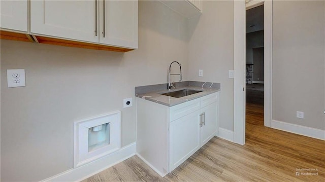 clothes washing area featuring cabinets, sink, hookup for an electric dryer, and light wood-type flooring