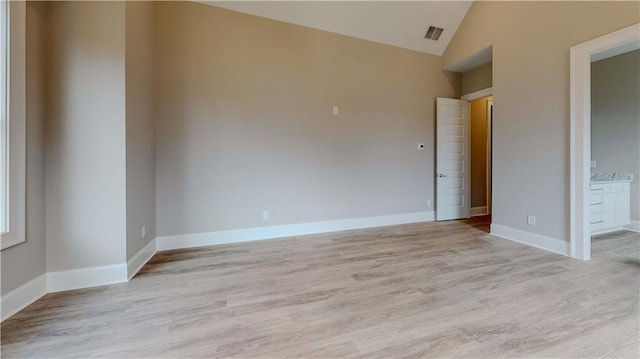 empty room featuring vaulted ceiling and light hardwood / wood-style flooring