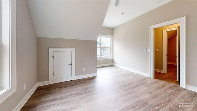 additional living space with light hardwood / wood-style floors and lofted ceiling