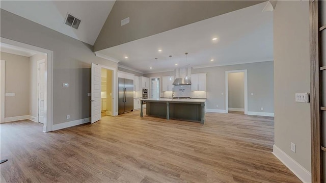 kitchen featuring decorative light fixtures, decorative backsplash, white cabinetry, an island with sink, and stainless steel built in refrigerator