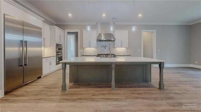 kitchen with a kitchen island with sink, a kitchen breakfast bar, stainless steel appliances, and white cabinetry