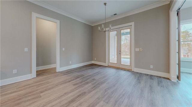 spare room featuring light hardwood / wood-style flooring, crown molding, and a notable chandelier