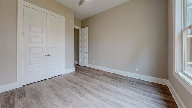 unfurnished bedroom with ceiling fan, a closet, and light wood-type flooring