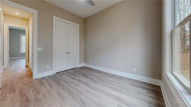 unfurnished bedroom with light wood-type flooring, a closet, and ceiling fan