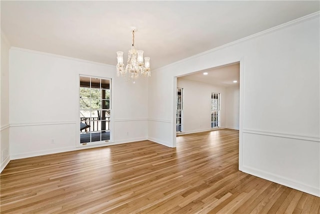 empty room with crown molding, a notable chandelier, and light wood-type flooring