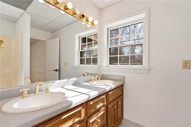 bathroom with vanity, a paneled ceiling, and a healthy amount of sunlight