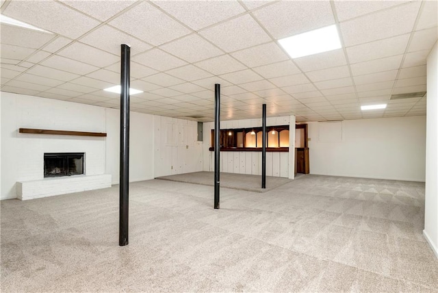 basement with a brick fireplace, light carpet, and a drop ceiling