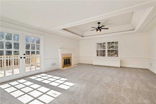 unfurnished living room with french doors, a fireplace, a raised ceiling, and carpet flooring