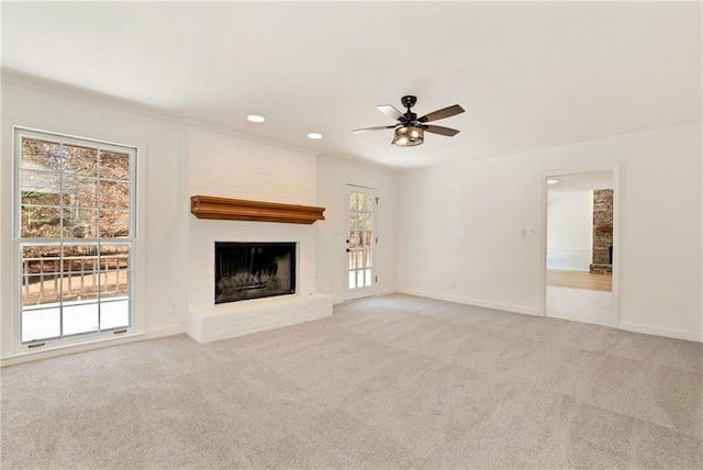 unfurnished living room featuring a large fireplace, light colored carpet, and ceiling fan