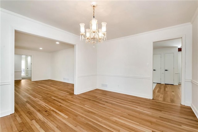 empty room with ornamental molding, light hardwood / wood-style floors, and a chandelier