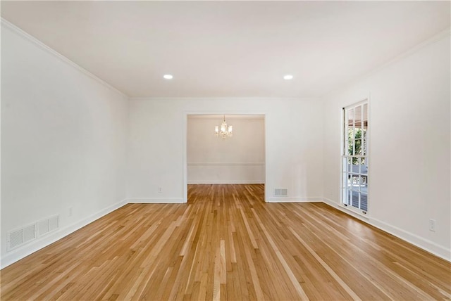 empty room with crown molding, light hardwood / wood-style floors, and a notable chandelier