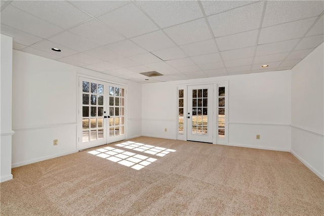 carpeted empty room with a drop ceiling and french doors