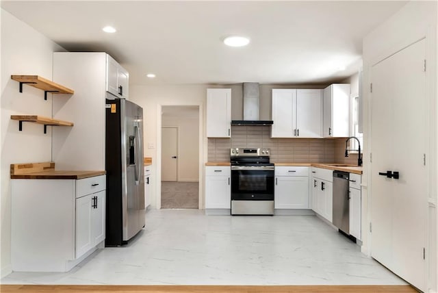 kitchen featuring sink, white cabinetry, appliances with stainless steel finishes, decorative backsplash, and wall chimney range hood