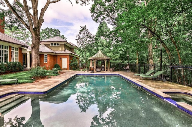 pool at dusk featuring an in ground hot tub, a gazebo, and a patio area