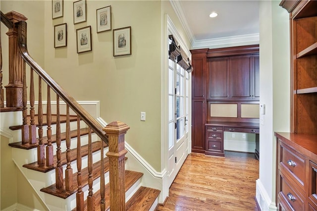 stairway featuring hardwood / wood-style flooring, built in desk, and crown molding