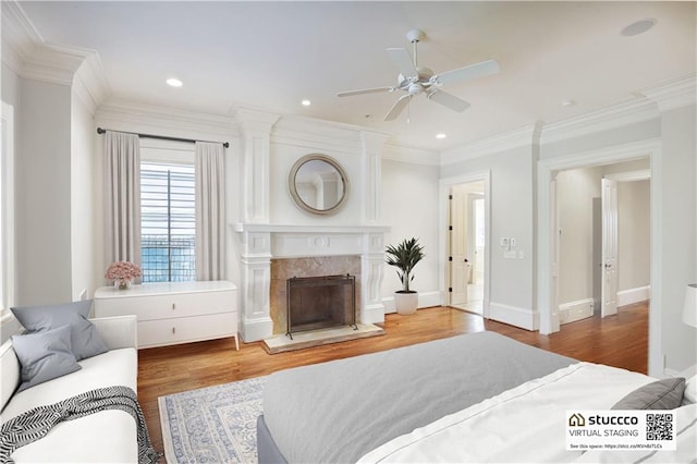 bedroom featuring a fireplace, hardwood / wood-style flooring, ceiling fan, and ornamental molding