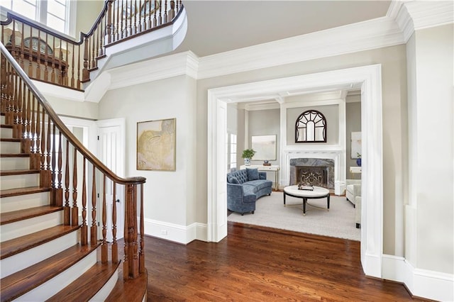 entrance foyer with a fireplace, ornamental molding, dark wood-type flooring, and a wealth of natural light