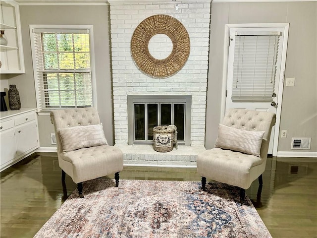 living area with a brick fireplace, dark hardwood / wood-style floors, and crown molding