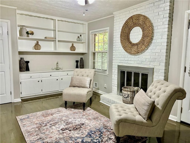 living area featuring a fireplace, a textured ceiling, ornamental molding, and dark hardwood / wood-style floors